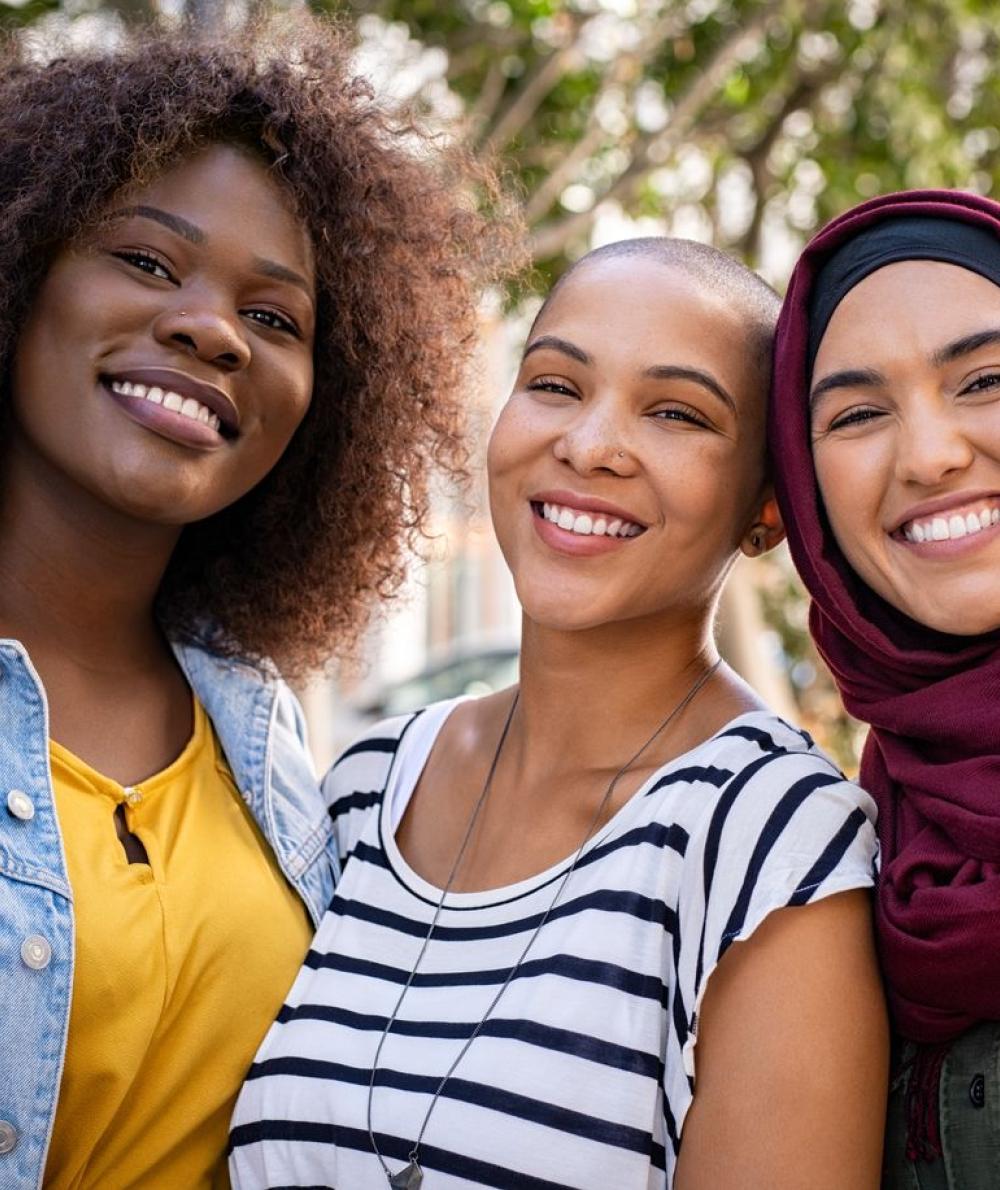 Three female students of differing ethnicities pose together while smiling