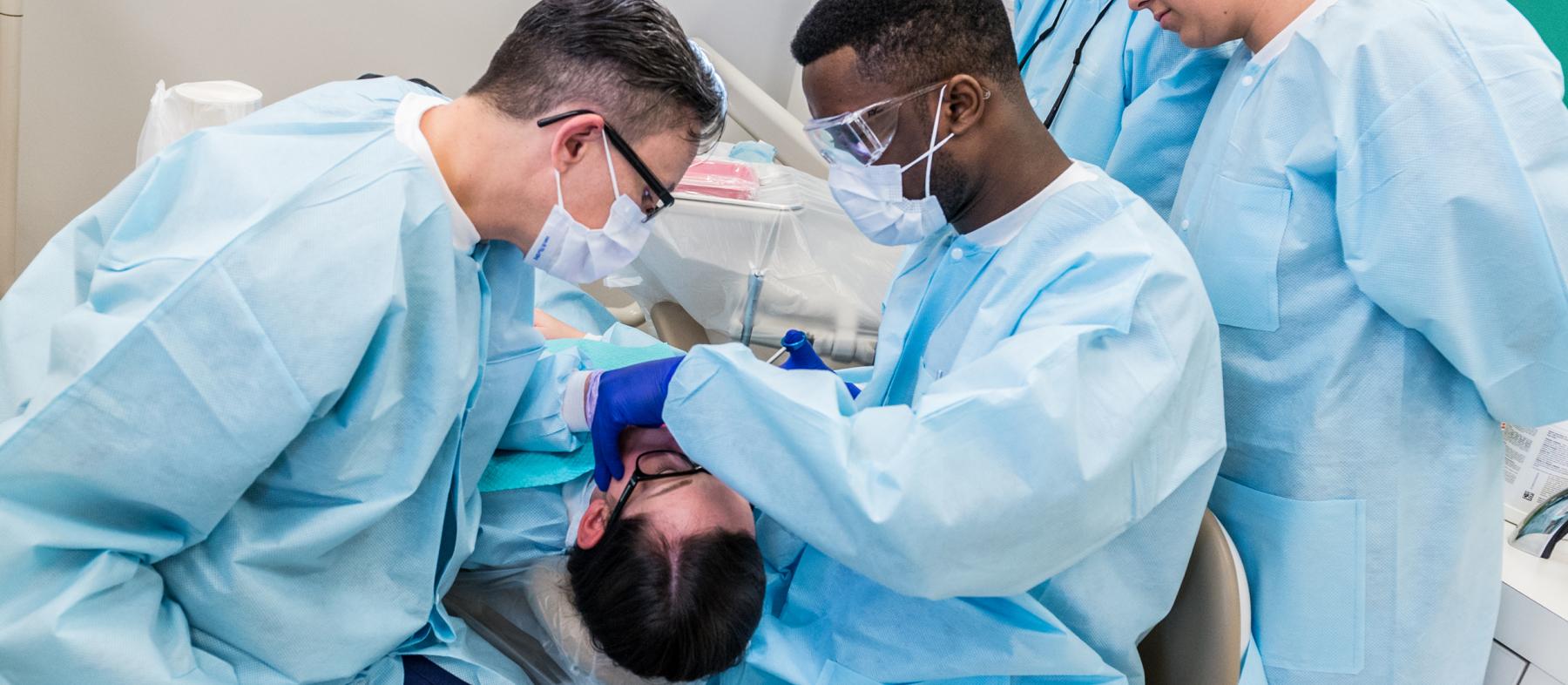 A student and professor work on a patient in a dental clinic