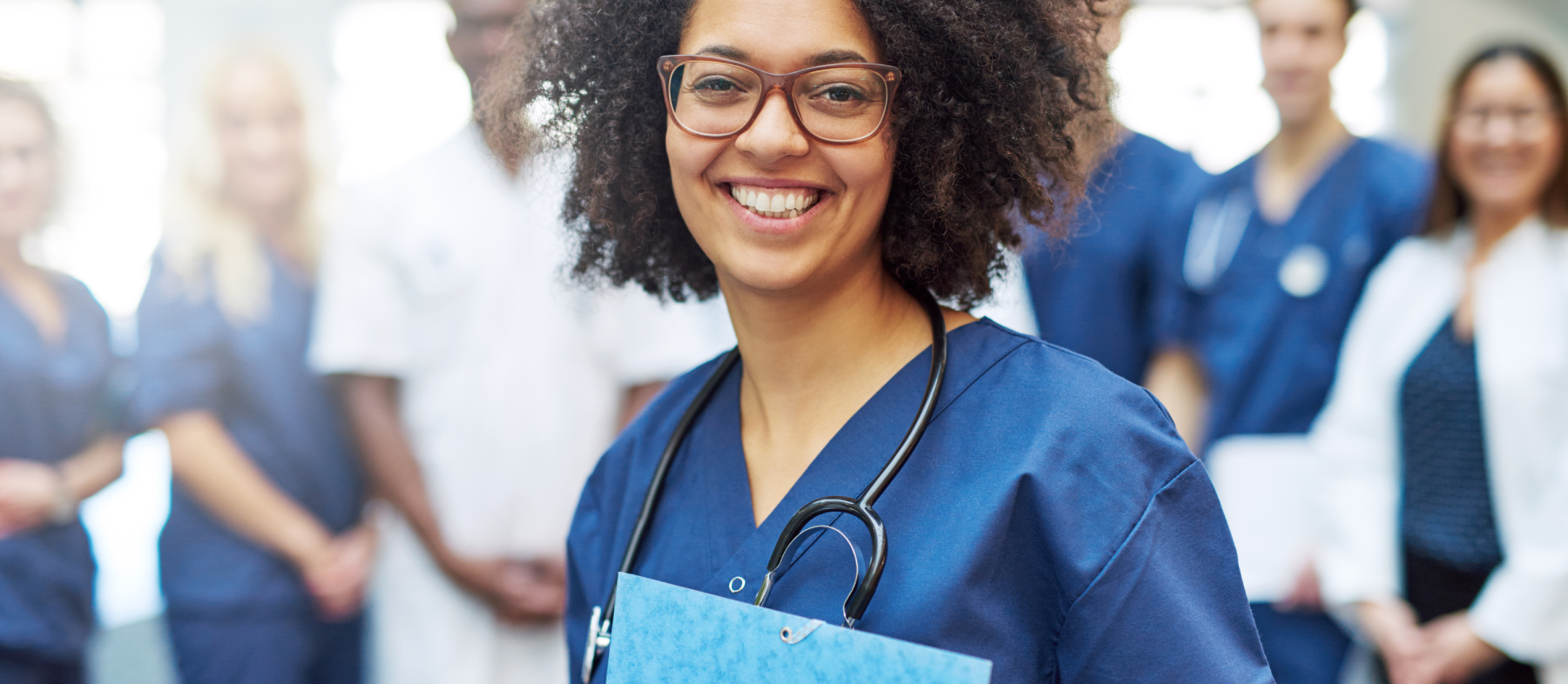 A woman in scrubs holds a folder