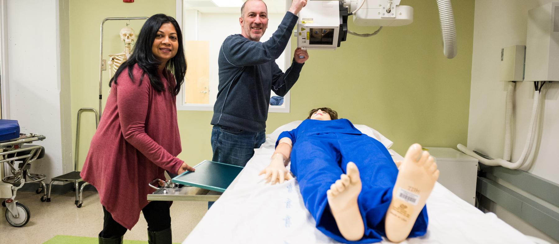 Two RT students use a dummy to practice with radiographic technology