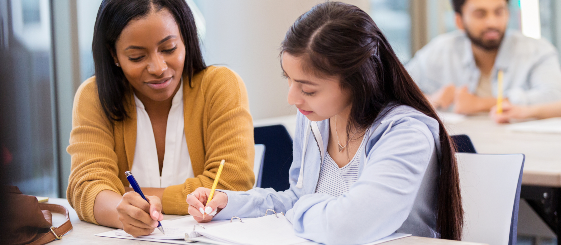 An advisor works with a high school student on some documents