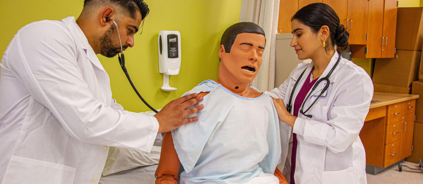 Two nursing students attend to a dummy