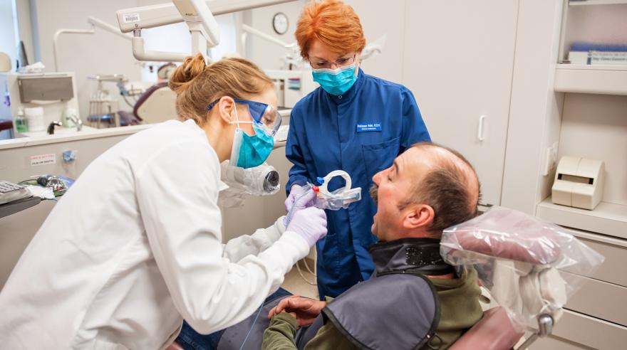 A student and instructor attend to a patient in the dental lab