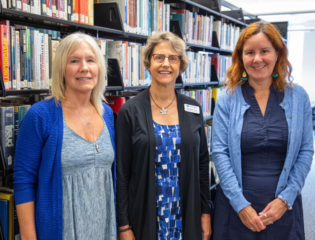 QCC’s library staff stand in front of the shelves