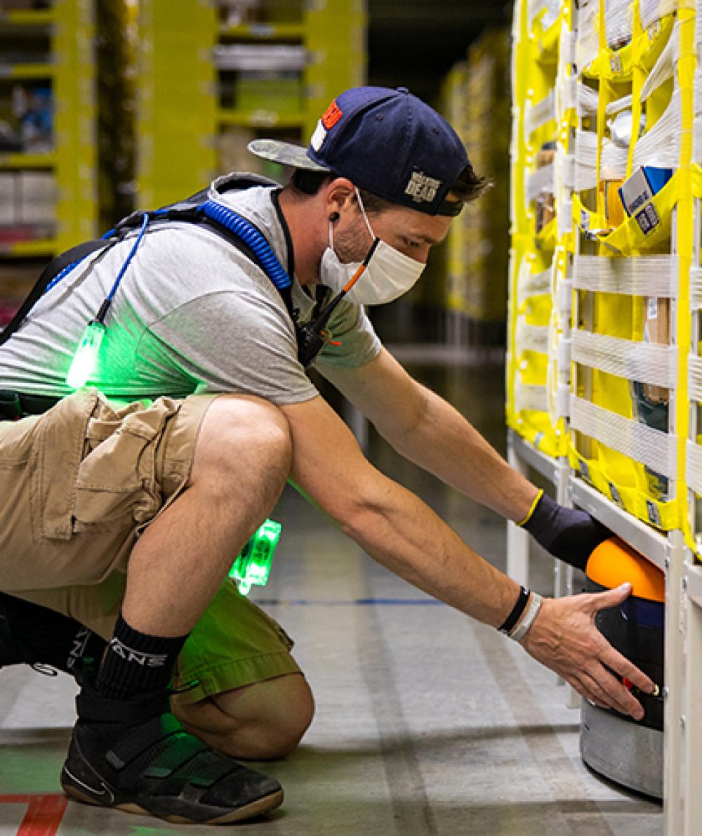 An amazon worker inspects shelves in a warehouse