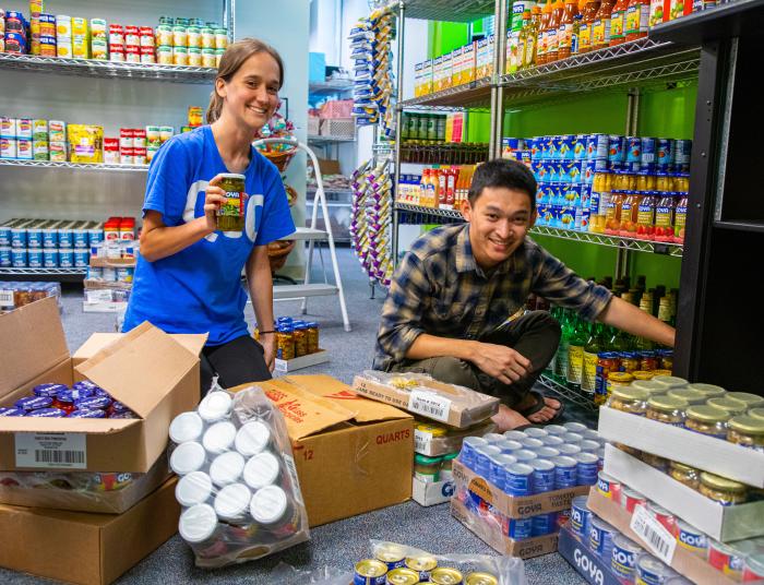 Two students volunteer to stock shelves in the food pantry