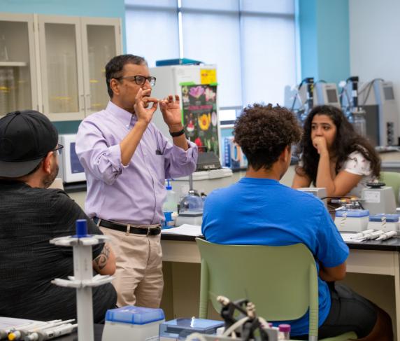 A professor teaches a group of STEM students in a biology lab