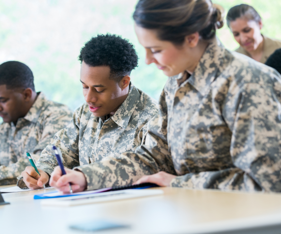 students in military uniform do paperwork in a classroom