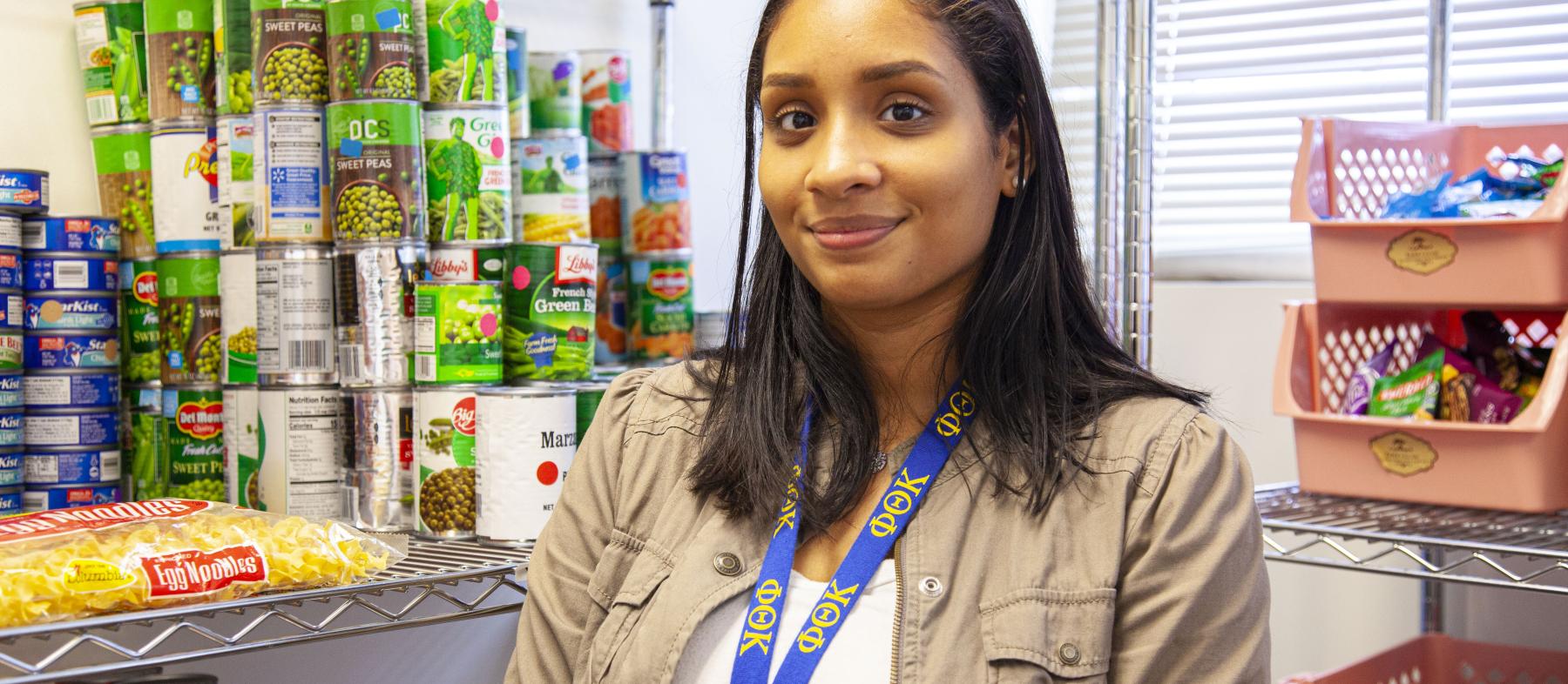 A woman stands next to shelves in the food pantry