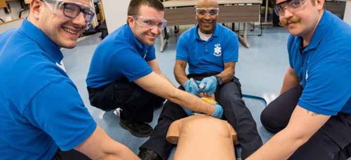 A class of paramedics practice on a dummy