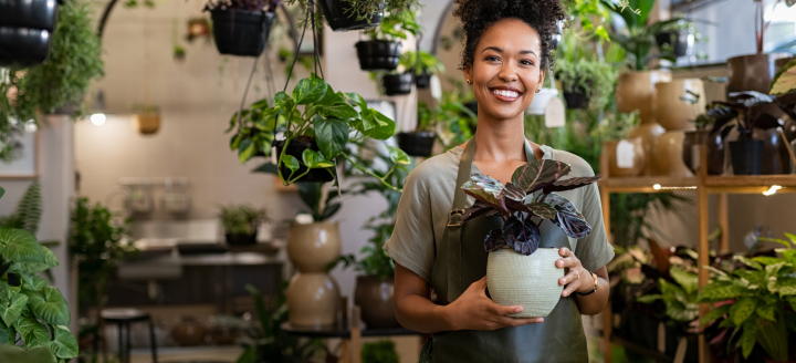 A female employee holds a potted plant in a plant shop