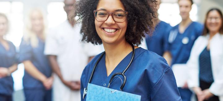 A woman in scrubs holds a folder