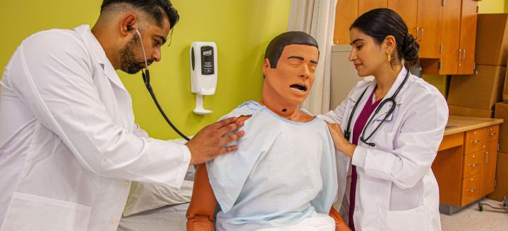 Two nursing students attend to a dummy