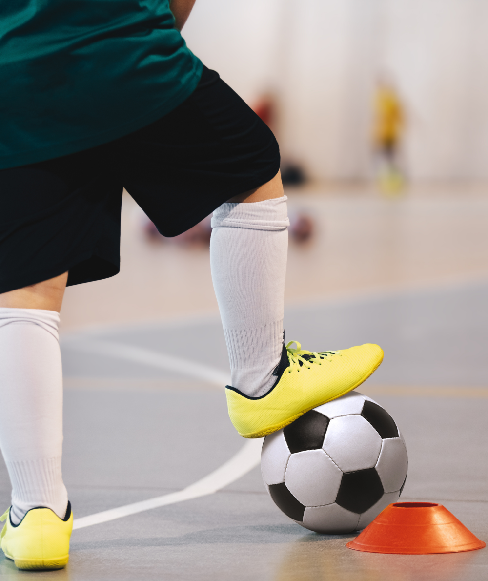 An indoor soccer player puts his foot on the soccer ball
