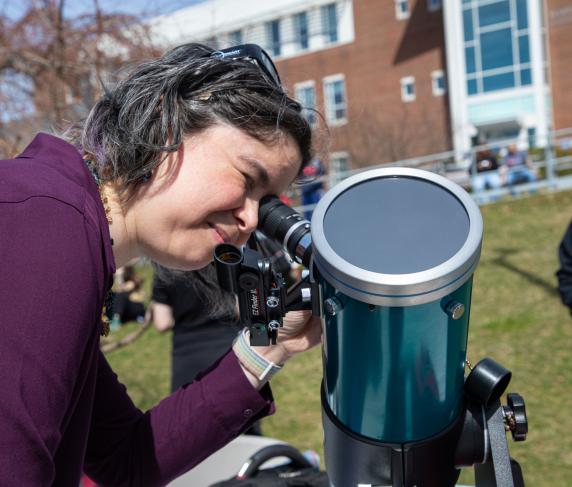 Professor of Integrated Science/Physics Andria Schwortz utilizing a telescope at the eclipse event.