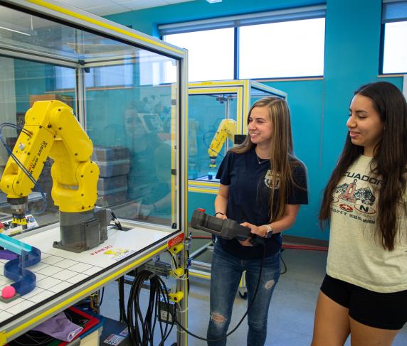 QCC graduate Anna Israelian (left) shows a potential student how to use a FANUC robot.