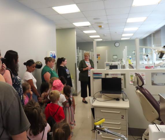 Dental Clinic Operations and Facilities Manager Sheryl Ficorilli (right) shows off dental equipment to the children.