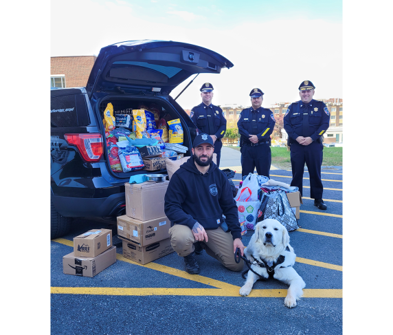 (front) Campus Police Officer Nick Yacuzzi with Community Resource Dog Siggy and (back, from left) Deputy Chief of Police Operations Mike Vigeant, Deputy Chief of Administration Reynaldo Rodriguez and Chief of Police Stephen DiGiovanni with a truckload of supplies for pets of hurricane victims.