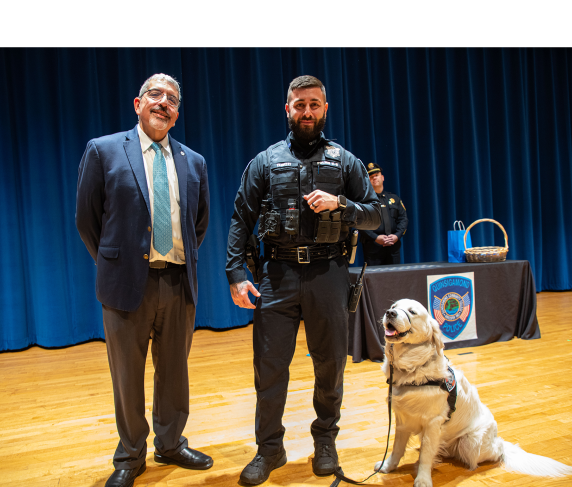 QCC President Dr. Luis Pedraja (left) and Community Resource Officer Nick Yacuzzi with Siggy sporting his new badge