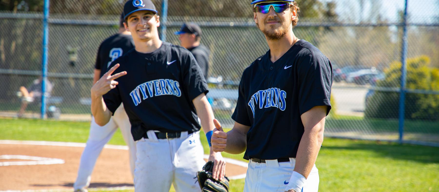 Two baseball players pose on field at a QCC Wyverns game.