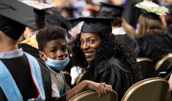 A mother holding her son wait in the seats at commencement