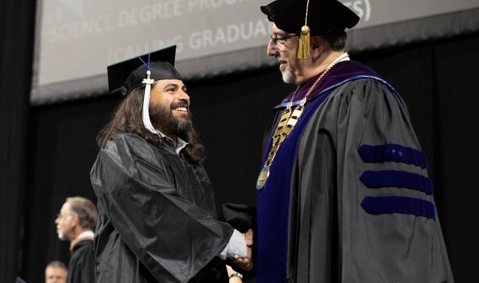 Dr. Luis Pedraja congratulating a student