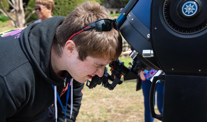 Student volunteer Aaron Bishop uses a QCC telescope to safely look at the eclipse.