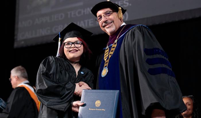 QCC President Dr. Luis Pedraja shares in the joy of receiving a diploma. QCC President Dr. Luis Pedraja shares in the joy of receiving a diploma.