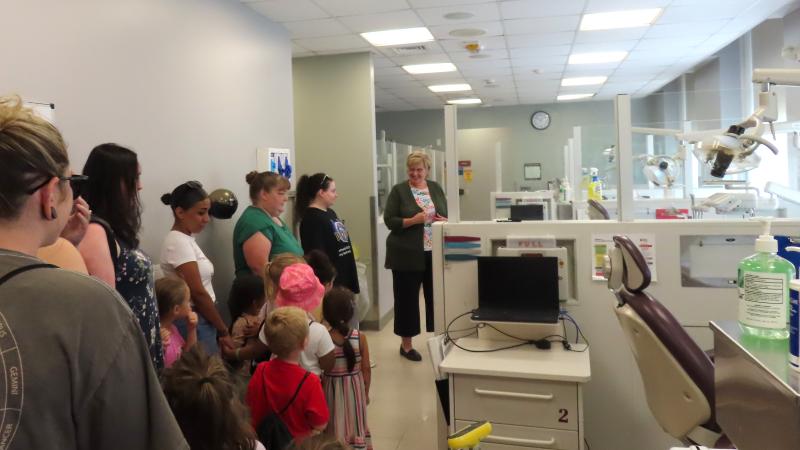 Dental Clinic Operations and Facilities Manager Sheryl Ficorilli (right) shows off dental equipment to the children.