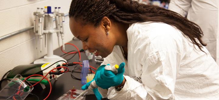 A QCC student uses a pipette in a science lab